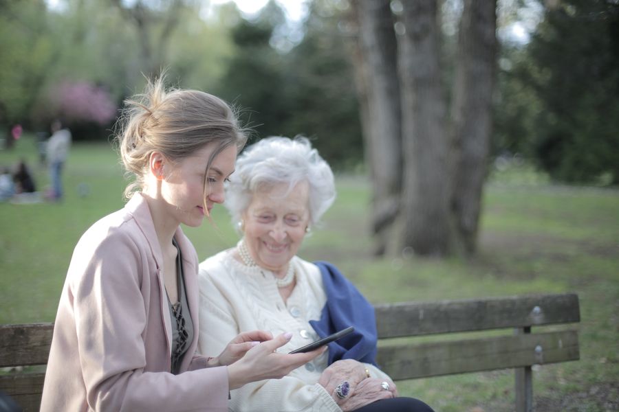 A helper showing a smiling senior woman how to use a phone
